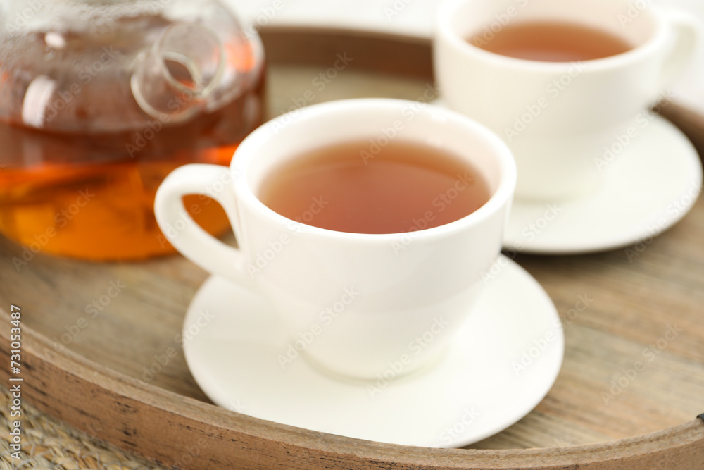 Aromatic tea in cups and teapot on wooden tray, closeup Aromatic tea in cups and teapot on wooden tray, closeup
