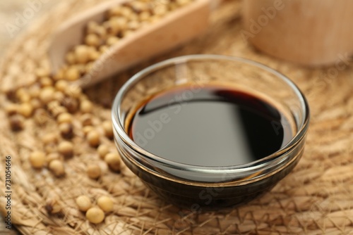 Soy sauce in bowl and beans on table, closeup