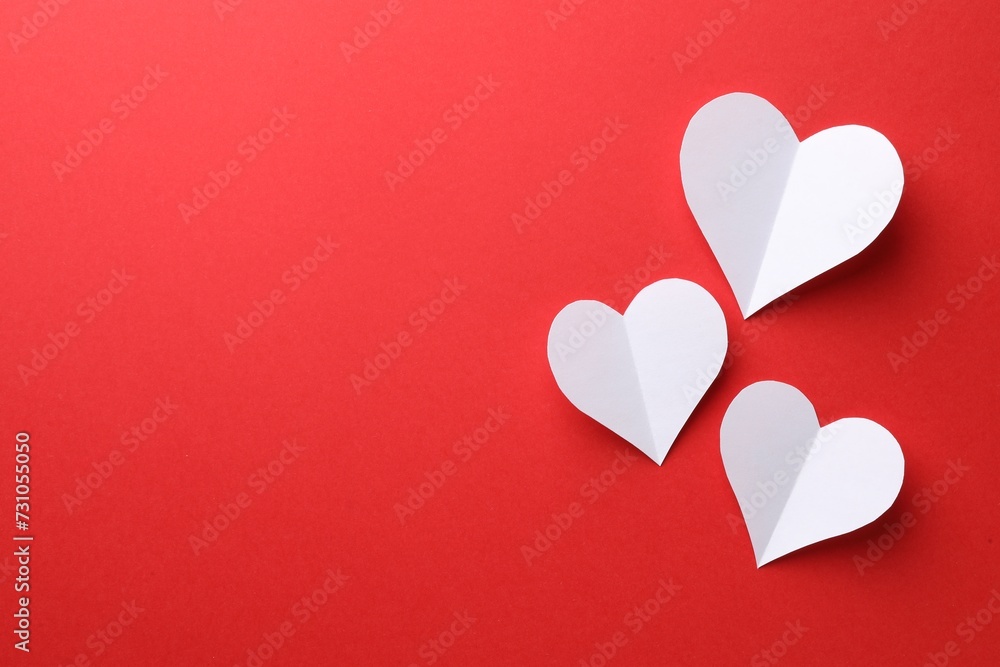 White paper hearts on red background, flat lay. Space for text White paper hearts on red background, flat lay. Space for text