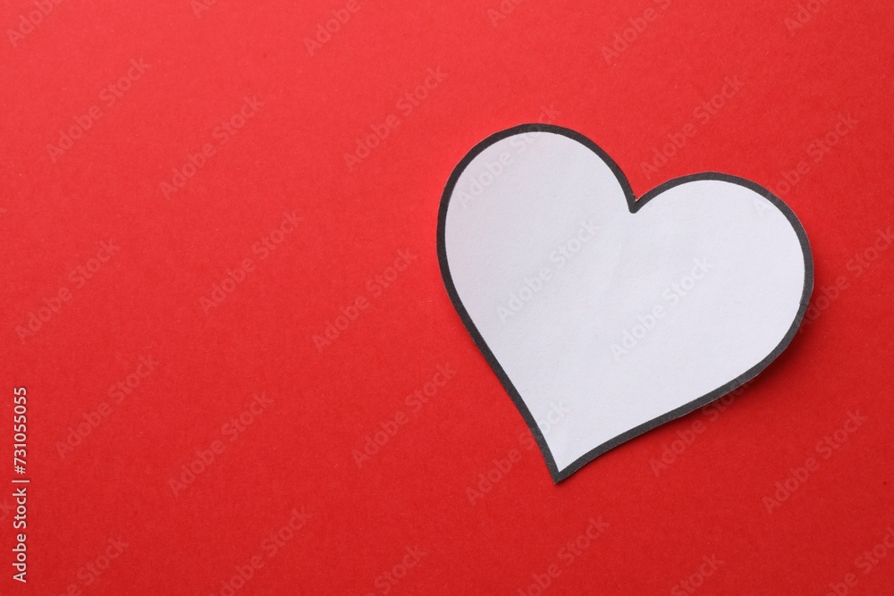 White paper heart on red background, top view. Space for text