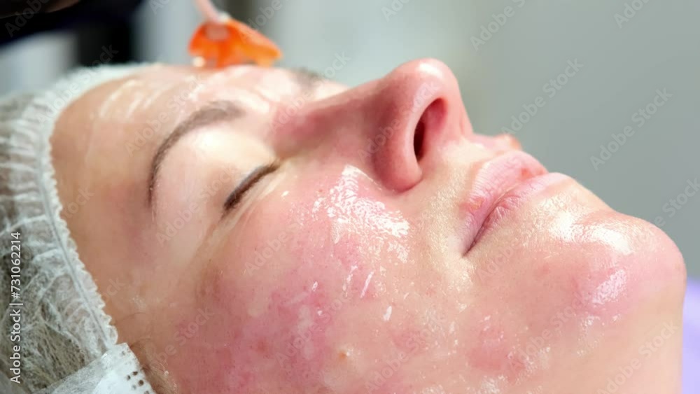 A cosmetologist applies a mask or care cosmetics to the face of a young client. Facial skin and anti-aging care. Cosmetology and professional facial skin care. A cosmetologist applies a mask or care cosmetics to the face of a young client. Facial skin and anti-aging care. Cosmetology and professional facial skin care.