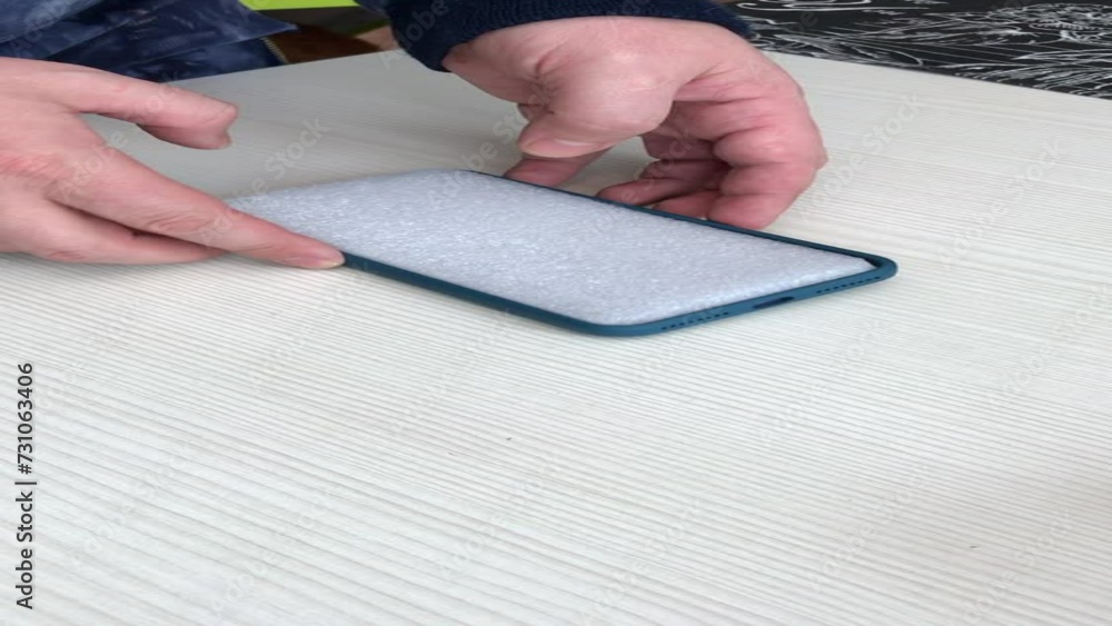 A man holds a blue smartphone case in his hands on the background of a wooden table. Vertical video. A man holds a blue smartphone case in his hands on the background of a wooden table. Vertical video.