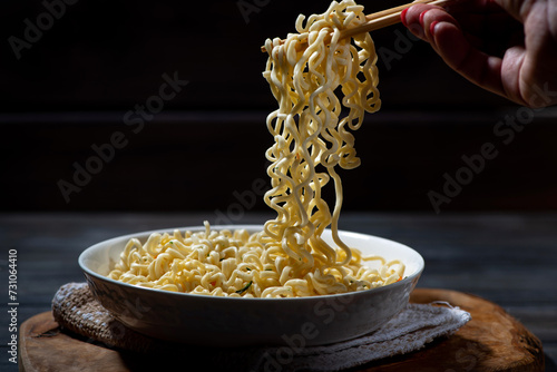 man takes a portion of hot noodles with chopsticks, horizontal