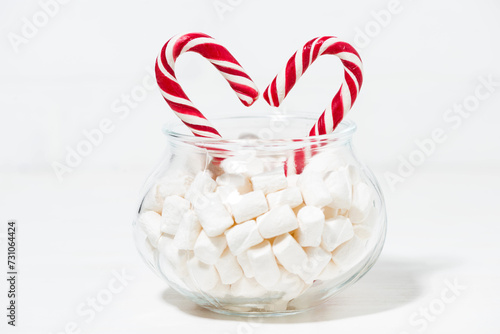 sugar candy in the shape of a heart in a jar of marshmallows on white background