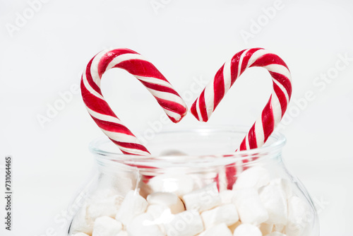 sugar candy in the shape of a heart in jar of marshmallows on white background, closeup