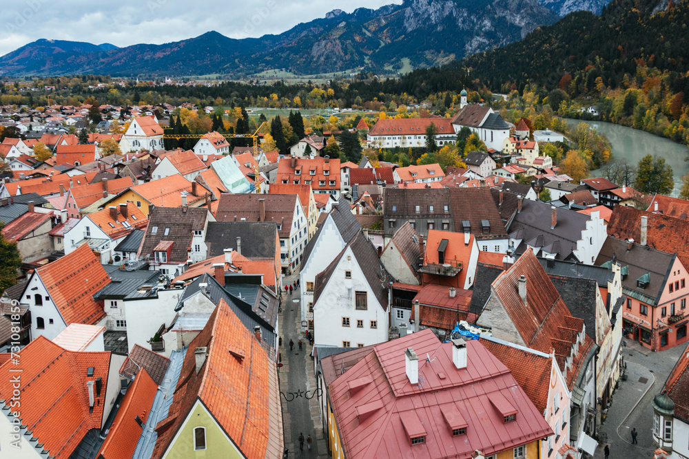 Obraz premium View from above of the old town of Füssen with orange roofed houses and the Lech River at the foot of the Bavarian alps