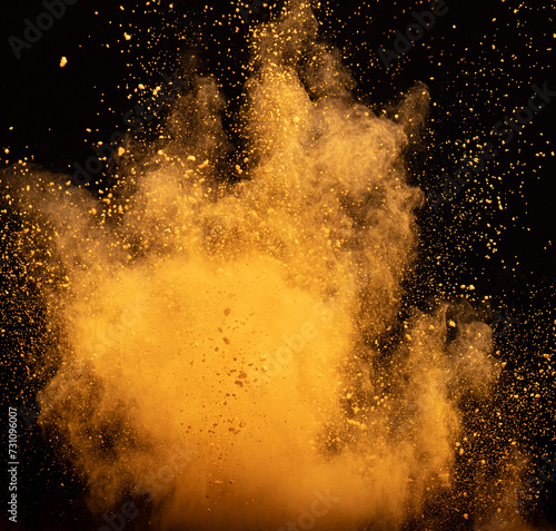 Explosion of orange powder, dust smoke on black background