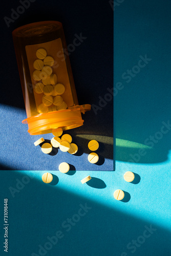 Bottle of tablet pills  spilled on blue background photo