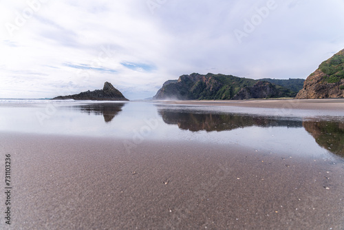 The massive black iron sand Karekare beach with picturesque rock formations out in the water. Waitakere Ranges Regional Park, Auckland, New Zealand. photo