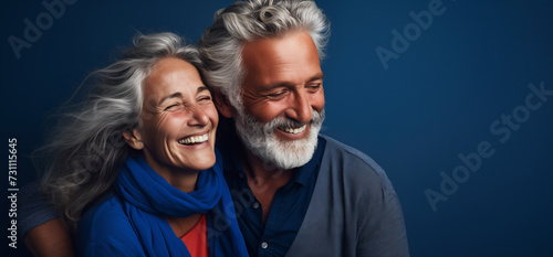 Un couple senior, heureux, amoureux, riant et partageant un moment de bonheur intense, arrière-plan bleu, image avec espace pour texte.