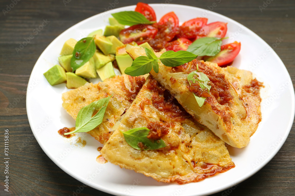 Delectable Tortilla de Patatas or Spanish Omelet Garnished with Aromatic Fresh Basil Leaves