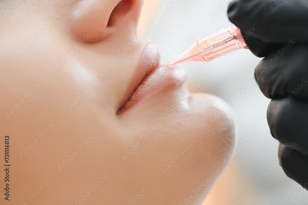 Young woman having permanent makeup on lips in beautician salon - obrazy, fototapety, plakaty 