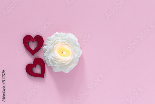 Red hearts and candle in flower shape on pink background. Valentine day and love concept. Top view with copy space for text.