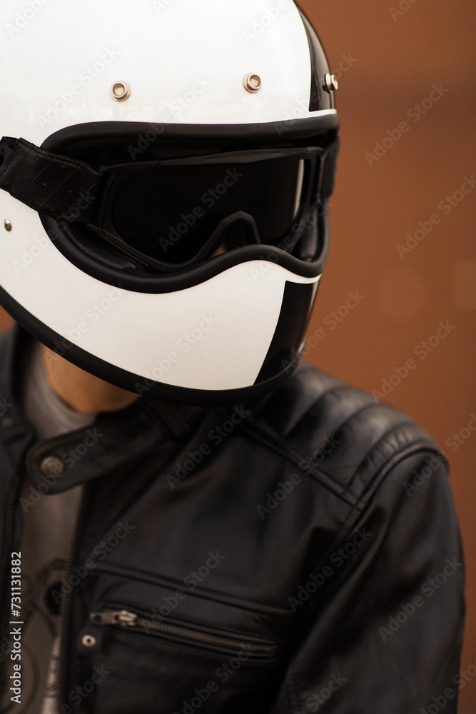 Close-up of a biker in a white helmet with goggles and a black leather jacket