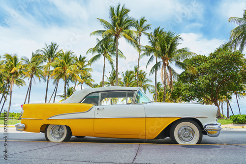 Yellow classic car on a tropical beach with palm tree, vintage process © Igor