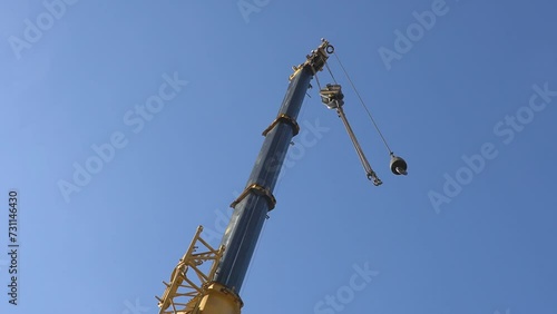 Mobile crane with hook and straps is raising work platform, basket.