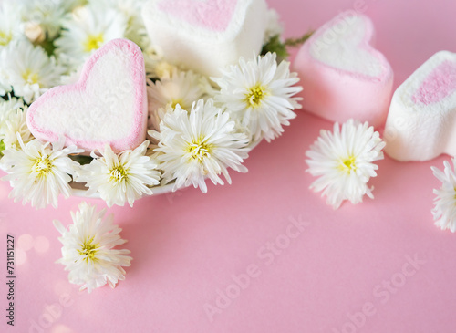 Pink marshmallows in the shape of a heart and white flowers on a pink background with copy space und bokeh. Valentine's Day, Mother's Day, Father's Day, Wedding. Sweet confectionery product.