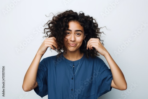 A woman with curly hair strikes a pose while being photographed  showcasing her unique hairstyle.