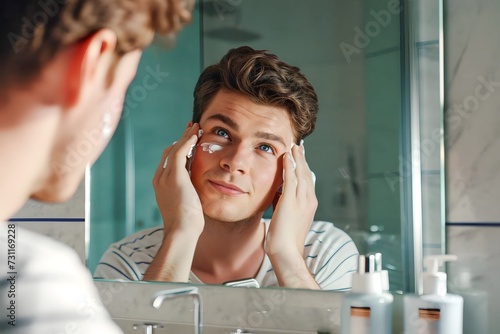 caucasian young man taking care of her skin applying lotion on her moisturizing face in front of the bathroom mirror