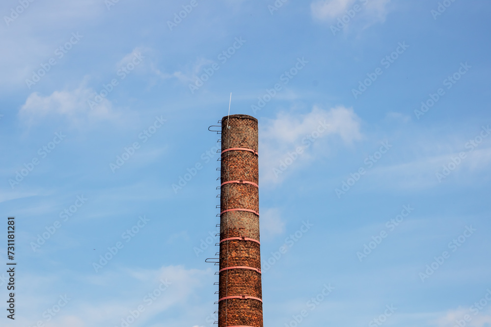 Brick chimney of factory on background of blue sky