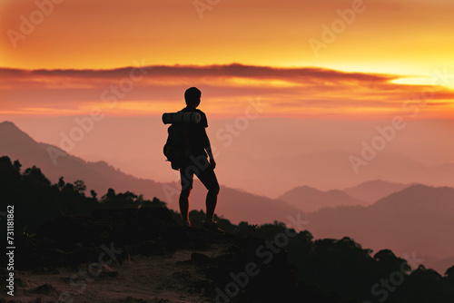 Silhouette of young hiker with backpack is standing in mountains