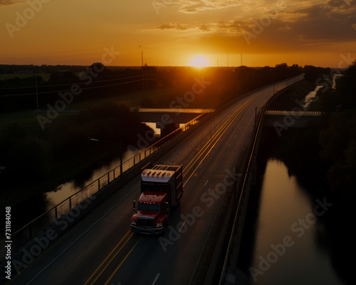 Red semi truck travels down highway at sunset.