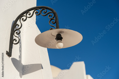 Street lamp with a light bulb on a white wall on a sunny clear day on the street in the resort town of Sharm El Sheikh, Egypt, closeup