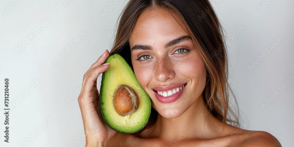 Healthy Lifestyle Concept of a Smiling Young Woman Holding Fresh Avocado Closeup on white background Healthy Lifestyle Concept of a Smiling Young Woman Holding Fresh Avocado Closeup on white background