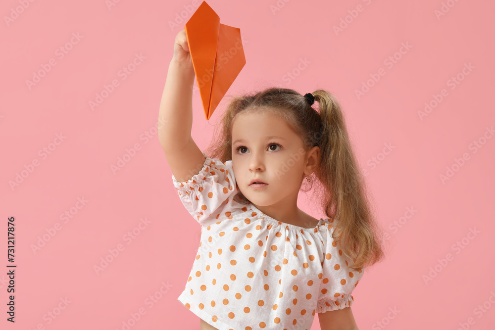 Cute little girl with paper plane on pink background Cute little girl with paper plane on pink background