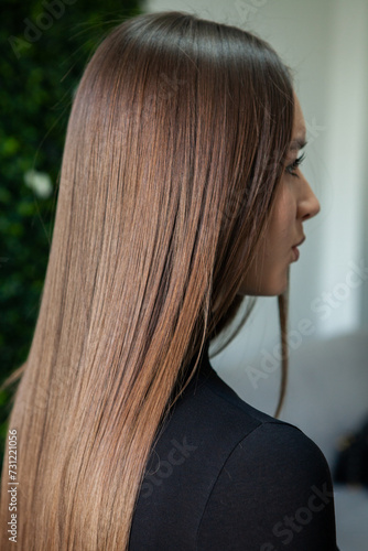 Photo of a European girl with long and beautiful brunette hair at the beauty salon. Shiny and healthy hair