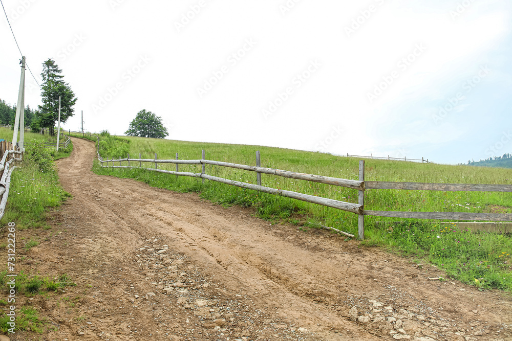 View of road with wooden fence and green grass View of road with wooden fence and green grass