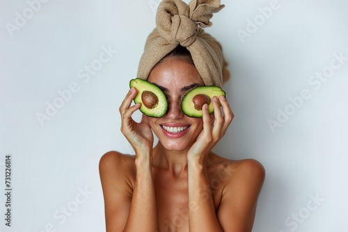 Smiling woman using avocado as organic skincare treatment