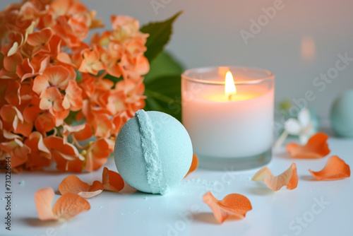 Orange green bath bombs with hortensia on white table, lit candle