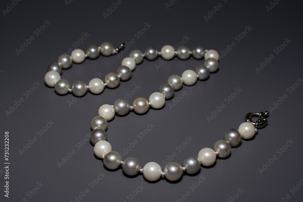 Pearl white round beads on a gray background. Women's elegant jewelry. Pearl white round beads on a gray background. Women's elegant jewelry.