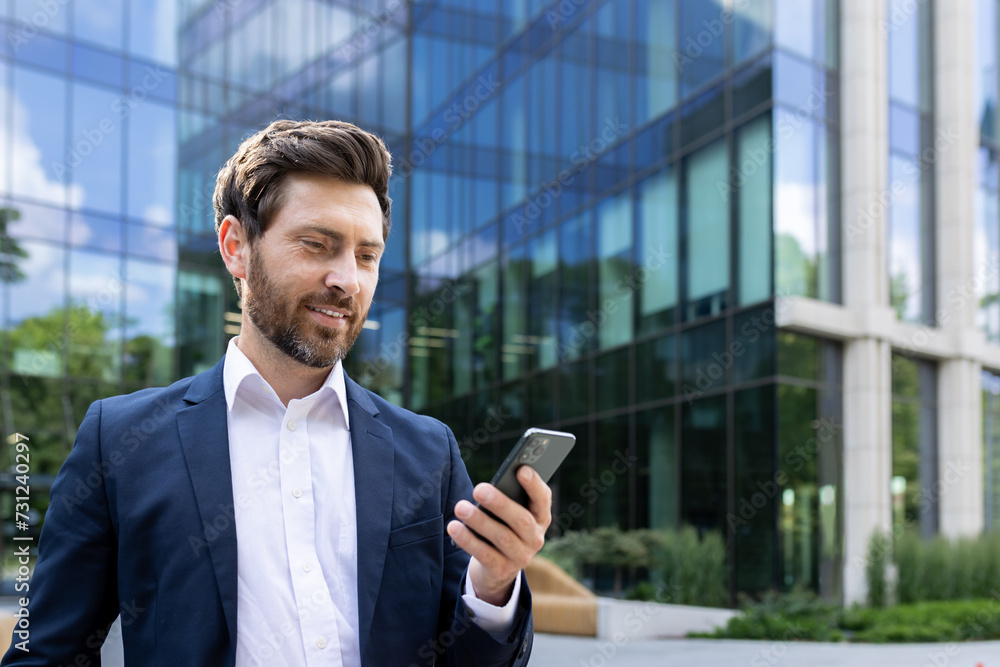 Confident businessman with smartphone outside modern office building, successful male leader Confident businessman with smartphone outside modern office building, successful male leader