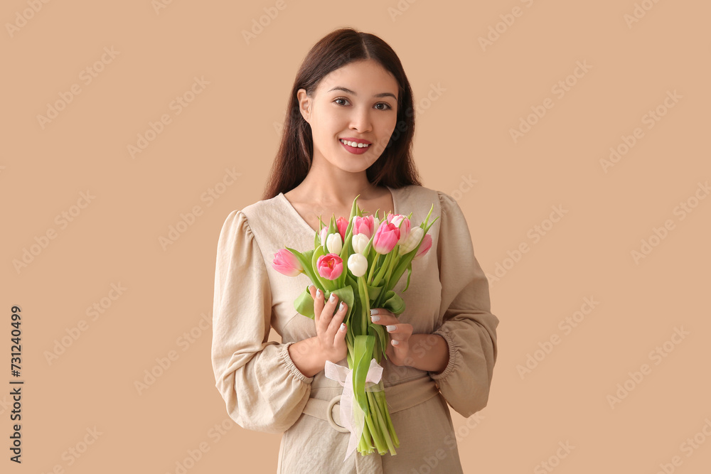 Pretty young Asian woman with bouquet of beautiful tulips on brown background. International Women's Day Pretty young Asian woman with bouquet of beautiful tulips on brown background. International Women's Day