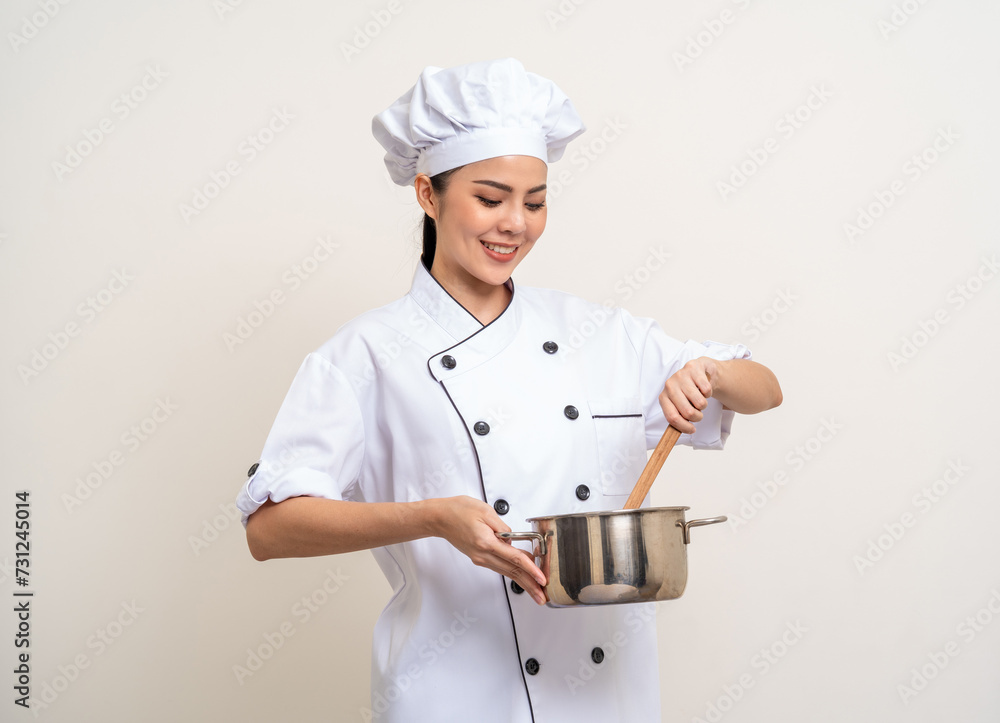 Young beautiful asian woman chef in uniform holding soup pot ladle utensils cooking in the kitchen various gesture menu good taste on isolated. Cooking woman chef people in kitchen restaurant