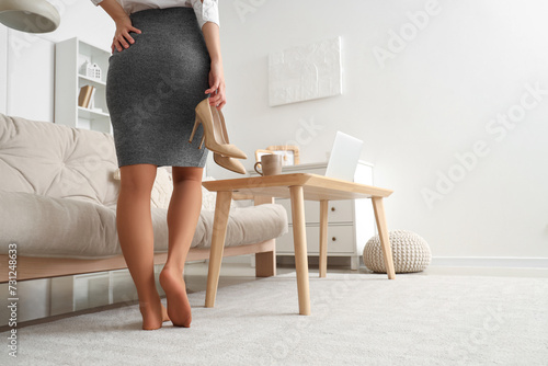 Businesswoman with her heels off at home, back view photo