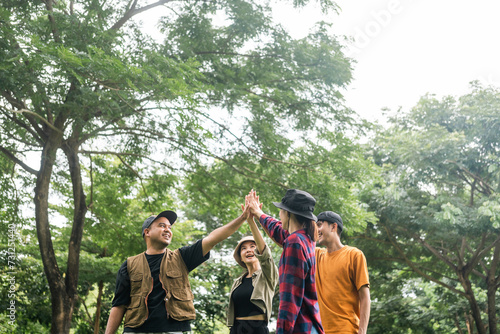 Group of young traveller people giving high five for friendship while camping in nature trip. Happy asian people group friend travel together. Enjoying camping on weekend vacation time.