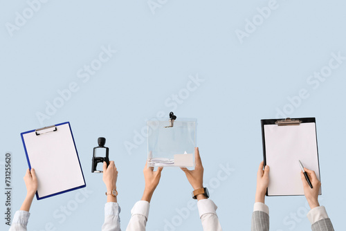 Hands holding ballot box and clipboards with voting papers on light background. Election concept