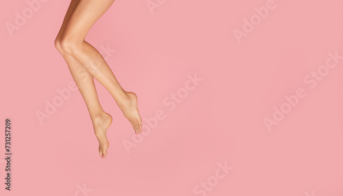 Slender and long female legs on a pastel pink background.