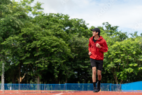 Attractive Young indian man wearing sportswear running on track at sport stadium. Asian Fit man jogging outdoor cross the finish line. Exercise in the morning. Healthy and active lifestyle concept.