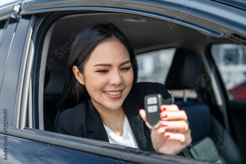 Young beautiful asian business women in suit getting new car showing car key. she very happy and excited in hand holding car key. Smiling female driving vehicle on the road city on a bright day © Chanakon