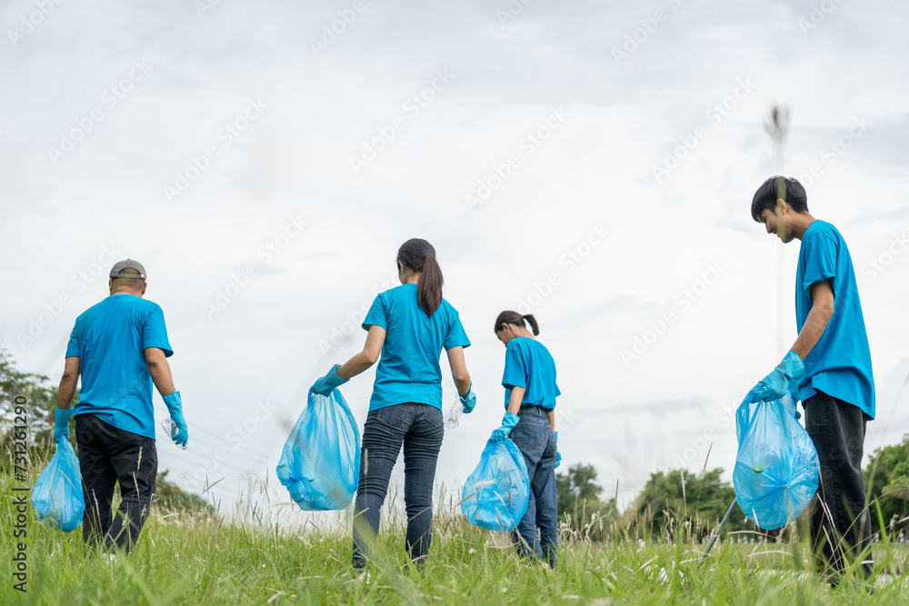 Happy volunteer people group charity with garbage bags cleaning up in park. Corporate social responsibility and society activity for Environment . Ecology and CSR concept.