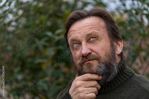 Portrait of a thinking or dreaming or solve problems senior man. Elderly bearded caucasian male in nature. Face bearded male daydream of decision, planning solution and insight of questions