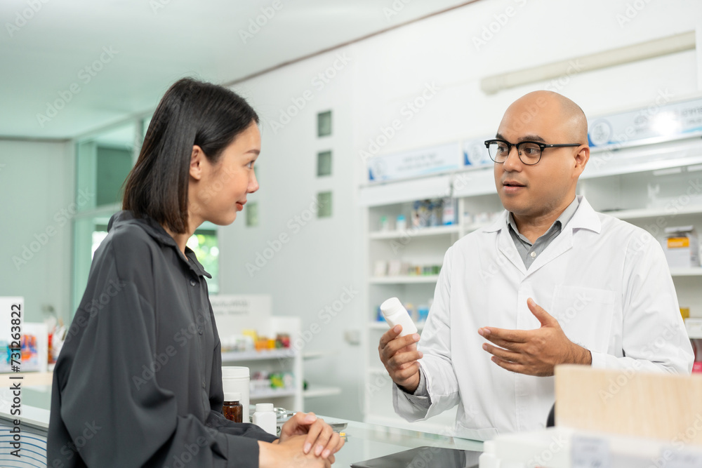 Pharmacist recommends medicines to customers. Asking the questions of medication. Professional Asian male pharmacist giving prescription medications to female patient customers at drugstore shelves.