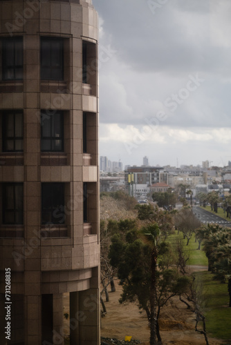 A modern high-rise stands along the Tel Aviv coast, with the skyline of Yafo (Jaffa) in the distance. The corporate office building expresses the bustling Israeli economy.