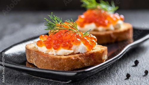closeup of appetizers toast with salmon and lumpfish roe in a black plate lumpfish roe