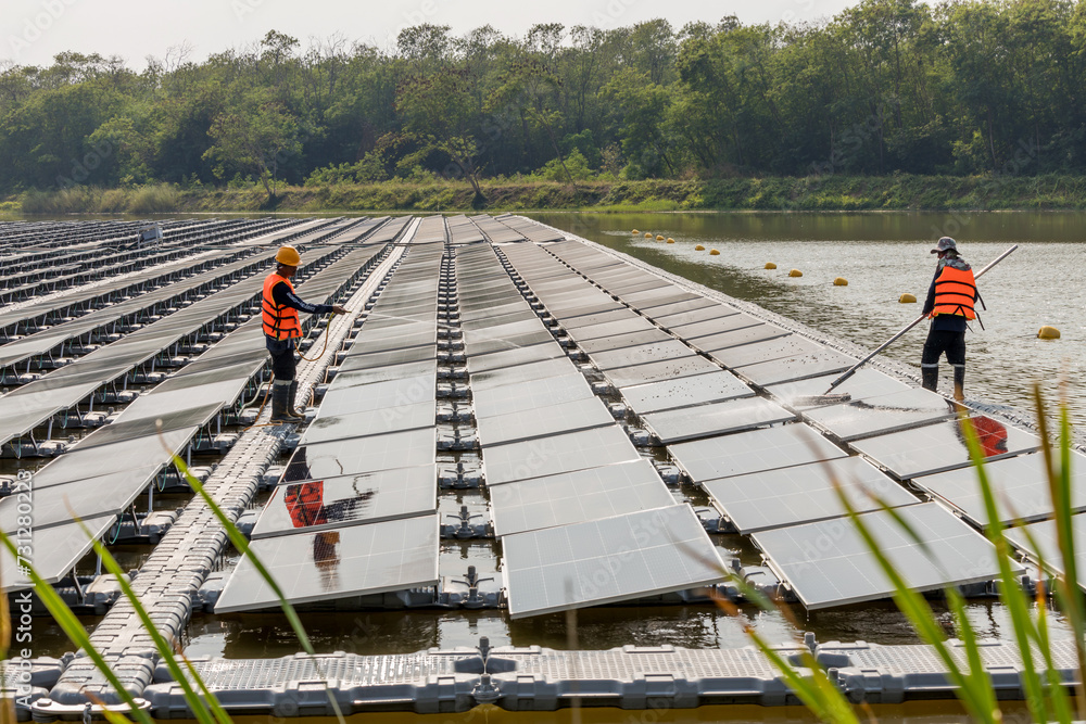 Naklejka premium Worker Cleaning floating solar panels or solar cell Platform system on the lake with brush and water. Worker cleaning solar modules in a Solar Energy Power Plant