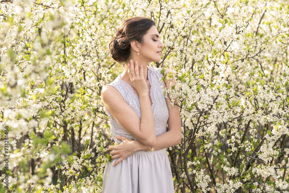 Beautiful brunette in a wedding dress in blooming trees. Beautiful brunette in a wedding dress in blooming trees.